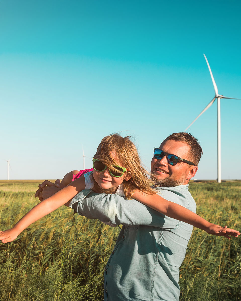 Father carrying daughter with windfarm in the background