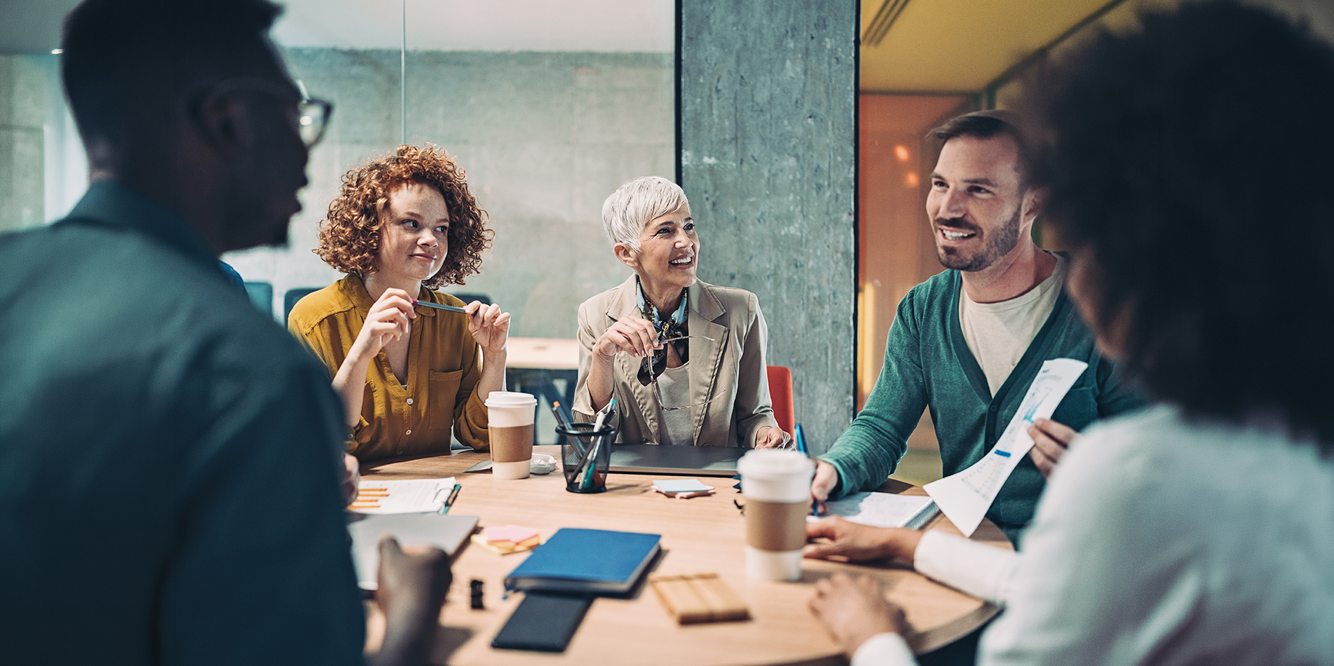 A diverse group of colleagues smiling and collaborating around a meeting table, discussing financial planning and income protection options.
