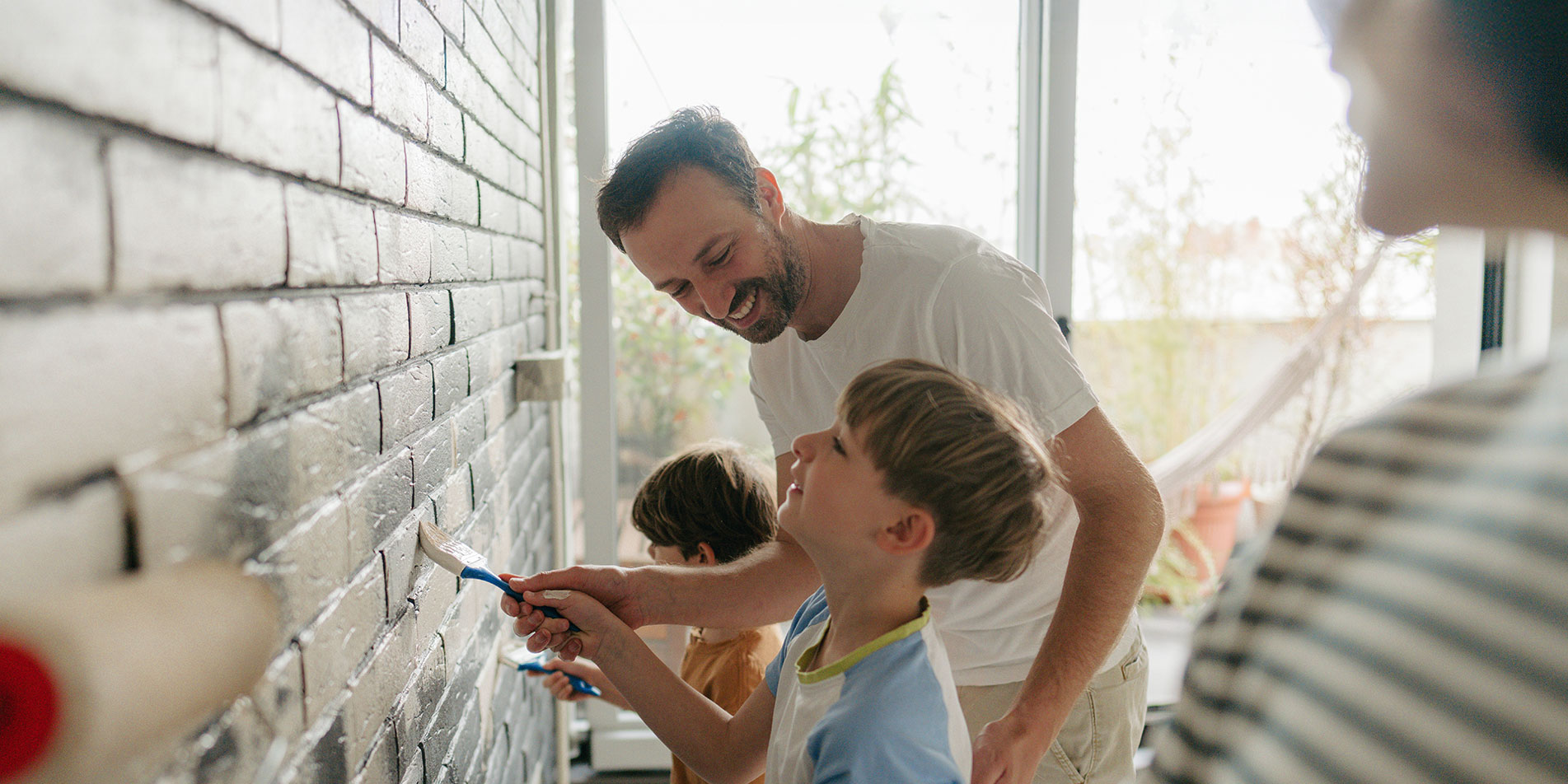 Family painting a brick wall
