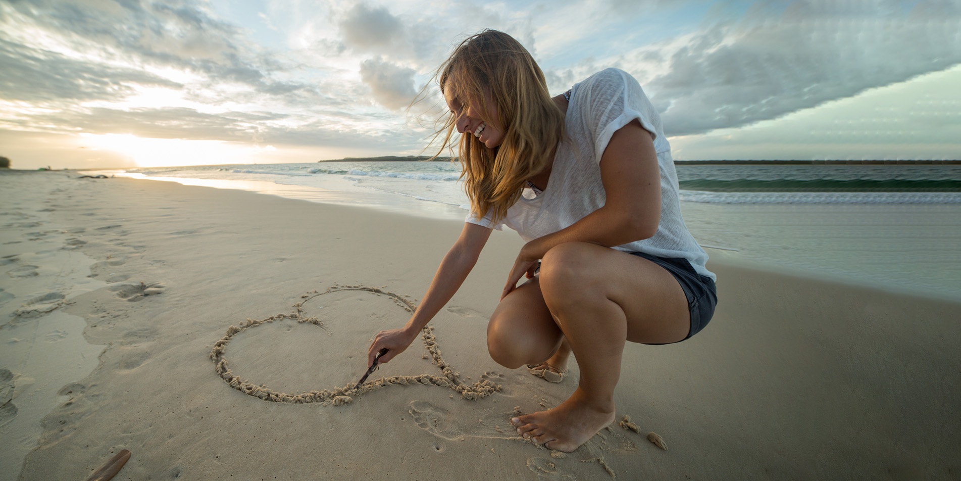 woman-draws-heart-on-beach-590162592